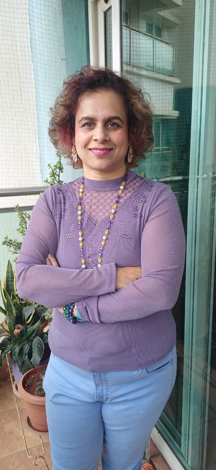 Shalaka wearing her crystal necklace and bracelets, standing in daylight